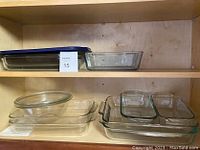 Shelf with various clear glass bakeware including rectangular dishes and bowls, showing overall lot contents.