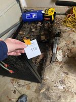 Photo showing hitch mounted cargo carrier platform with mesh base and folded sides, used condition, taken from top-down angle.