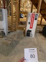 Charcoal Weber grill in original boxed packaging and metal animal catch trap cage.