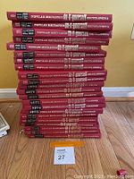 Stack of 22 books showing the spines with popular mechanics do-it-yourself encyclopedia and yearbook titles, various years 1973 to 1978, with red covers and white and yellow text.