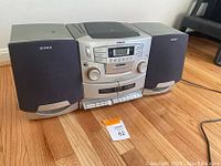 Front view of Sony stereo system showing CD tray, cassette player, and speakers on hardwood floor.