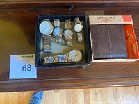 Photo of Dockers unopened wallet and five wristwatches displayed inside a black box on wooden surface.