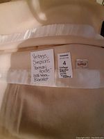 Close-up image showing the blanket label with brand name Simpsons Harmony House and handwritten description card stating it is a 100% wool blanket of queen size.