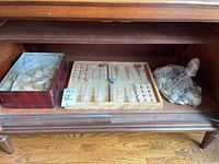 View inside wooden cabinet showing onyx backgammon board, stone pieces, dice, and bags of rocks in plastic bags.
