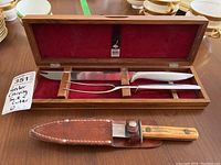 Carving set in wooden case with leather-sheathed knife below