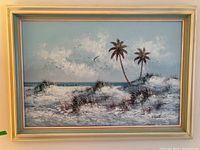 Full view of Engel oil painting framed, showing seaside landscape with sand dunes, two palm trees and flying birds.