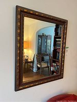 Full view of the rectangular wood framed mirror hanging on the wall, showing reflection of room.
