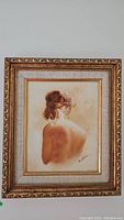 Framed painting showing the woman’s back in warm tones, full view