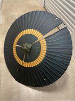 Top view of the antique Japanese umbrella showing a large tear, concentric ring design in yellow and dark blue, and weathered fabric.