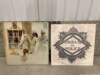 Two vinyl LP covers by Cheap Trick. One shows the band dressed in white uniforms with a dog lying in front; the other is an inner sleeve with the Dream Police logo and lyrics.