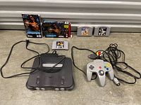 Nintendo 64 console with controller and 4 game cartridges laid out on floor