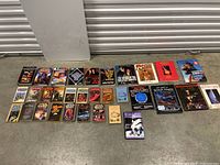 Wide shot showing entire lot of 29 sci-fi books laid out on floor with visible covers including Star Wars, Conan, Star Trek and others