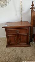 Wooden Drexel nightstand with drawer and lower cabinet doors, side angle view.