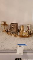 Gold-plated mirrored tray holding tissue box cover, perfume bottles, floral note holder