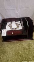 Wooden desk organizer with one drawer and multiple compartments, with necklace and earrings displayed in the drawer
