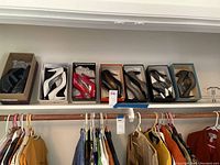 Six pairs of women's shoes on a closet shelf. Various styles and colors including flats, heels, and peep-toe shoes. Shoes in shoeboxes or loose. Sizes 9-9.5.