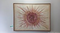 Full view of framed abstract painting on canvas with sunburst theme in warm tones.