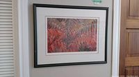 Framed limited edition print featuring botanical artwork in red hues, hanging on wall.
