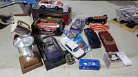 Overview of the lot showing multiple collectors car models, a trophy and pewter golf cup on table.