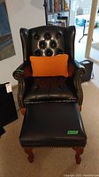 Front view of chair and matching stool with orange pillow