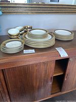 Full set displayed on wood cabinet: plates, cups and saucers with gold and blue pattern.