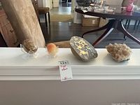 Wide view of all four items arranged in a row including two stone eggs on stands, a septarian slab, and a crystal formation cluster.