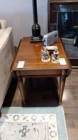 Top view of polished wood drop leaf end table with a lamp and figurines on top, showing its rectangular shape and finished surface.