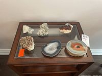Full view of two geodes and four crystal formations arranged on a glass table