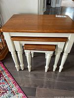 Three wood nesting tables, largest is 22x14x21 inches, stacked together showing white legs and natural wood tops.
