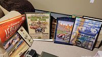 Photo of the entire set of framed and unframed vintage racing posters arranged leaning against a wall and on the floor.