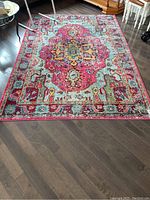 Full view of the colorful area rug on hardwood floor showing central medallion and surrounding pattern.