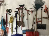 Wide view showing various shovels, rakes, cords, and hand tools hung on pegboard