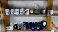 White ceramic beer steins and assorted glassware on a shelf