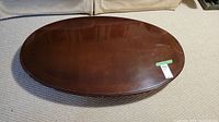 Oval wooden table top shown from top with dark finish and some wear marks