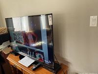 Photo showing the Samsung 50-inch LED TV on a stand with remote controls in front.