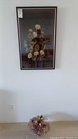Full view of the framed fabric floral tapestry hanging on a white wall, size visible in relation to outlet and wall space.