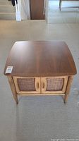 Top front view of mahogany side table showing caned double doors and wooden handles.
