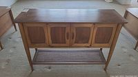Full front view of sideboard showing four paneled doors and caned lower shelf