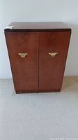 Closed front view of walnut-tone wood cabinet with brass-tone pulls
