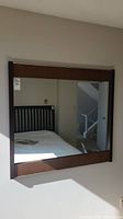 Front view of mid-century modern mirror mounted on wall showing full reflective surface and wooden frame detail.