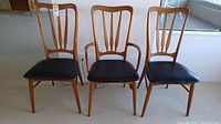 Three teak dining chairs (two side chairs and one armchair) arranged front-facing to show overall style and upholstery.