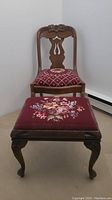 Photo showing full view of chair and stool together, highlighting the embroidered upholstery and carved wood