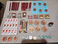 Overview of all makeup items laid out on a surface including lip liners, eyeshadows, blushes, bronzers, and brushes.
