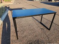 View of black desk/table from a straight position showing full structure and surface