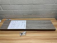 Photo showing top surface of floating shelf with installation instructions and mounting hardware bag on top.