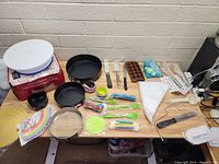 Top view of large lot of cake decorating pans, baking tools, and accessories laid out on table.