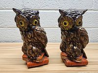 Front view of two vintage owl figurines side by side on wooden surface.