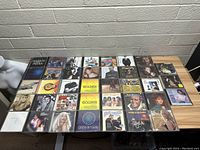 Photo showing a wide view of 28 various music CDs on a table, with visible artist names and album art.