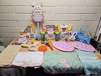 Full overview of lot showcasing towels, headbands, trays, cups, and various small Easter decorations arranged on table.