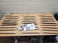 Overview of the pants hangers laid out on a wooden table with packaging and clips visible